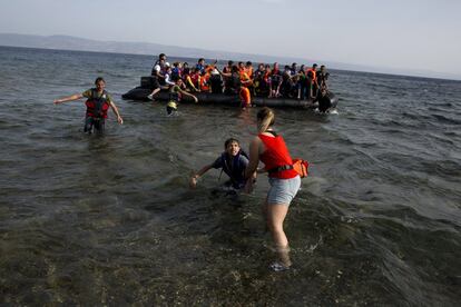 La guardia costera griega y un transbordador rescataron este lunes a 61 personas que naufragaron en un bote al intentar llegar a las costas helenas desde Turquía. En la imagen, una voluntaria ayuda a un grupo de refugiados a su llegada a la isla griega de Lesbos.