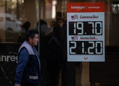 Un hombre pasa frente a un banco que anuncia los precios por compra y venta de dólares, en Ciudad de México.