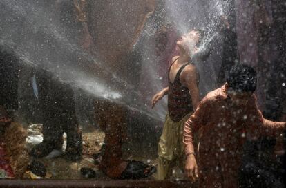 Niños se refrescan con agua proveniente de cañerías después de perforarlas en protesta contra los apagones en su área, en Karachi, Pakistán.