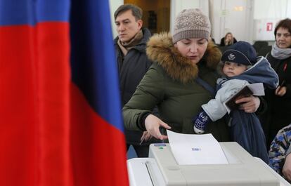 Una mujer sujeta a sus bebé después de votar enSovkhoz Imeni Lenina.