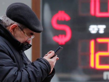 Un hombre consulta su teléfono delante de una casa de cambio de moneda, en San Petersburgo.