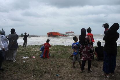 TOPSHOTS
This picture taken on December 18, 2014 shows residents watching as an Indonesia-registered tanker lies in rough sea close to the shore after it was pushed by strong winds during stormy weather in the Thai southern city of Narathiwat.  Parts of southern Thailand have experienced floods in recent days after heavy rains hit the region.   AFP PHOTO / Madaree TOHLALA