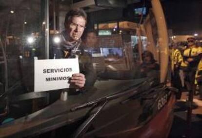 Un empleado de Transportes Metropolitanos de Barcelona coloca un cartel de servicios mínimos en uno de los autobuses de las cocheras de la Zona Franca de Barcelona en la huelga de marzo pasado. EFE/Archivo