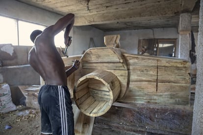 Mensah Silas tiene 19 años y talla ataúdes de fantasía en Hello Design Coffins, el taller de su padre, en el distrito de Teshie en Accra. En Ghana, las personas aspiran a ser enterradas en ataúdes que representan su trabajo o algo que amaban en la vida. Un Mercedes-Benz para un empresario, un pez para un pescador, un secador para una peluquera o una cámara para un fotógrafo. Un ataúd puede costar desde 500 a 6.000 Gh¢ (entre 95 euros y 1.200 al cambio). El salario mínimo interprofesional en Ghana es de unos 60 euros al mes y el coste de un funeral varía entre los 5.000 euros y 15.000.