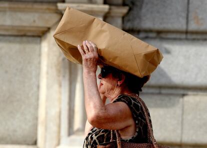 Una mujer se cubre la cabeza con una bolsa de papel frente al Palacio Real (Madrid). 