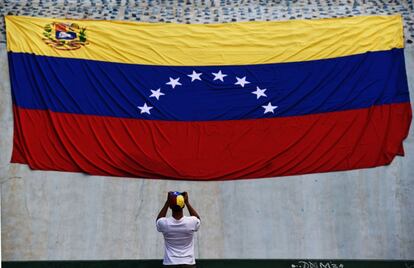 Un hombre saca una fotografía de la bandera nacional, en Caracas. 