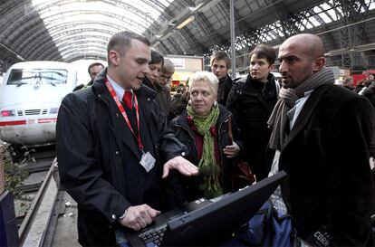 Un trabajador de la compañía de Deutsche Bahn de tren informa en Franckfurt a los pasajeros del retraso sufrido por su convoy debido al temporal.