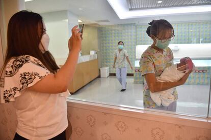 Una mujer hace una foto de un recién nacido protegido con una pantalla facial.