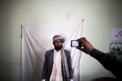 Un trabajador realiza una fotografía a un residente para emitir su tarjeta de votante, para las próximas elecciones presidenciales, en un centro de registro en la ciudad de Herat (Afganistán).