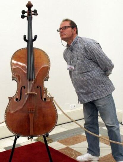 Un visitante observa el violonchelo restaurado en una sala del Palacio Real.