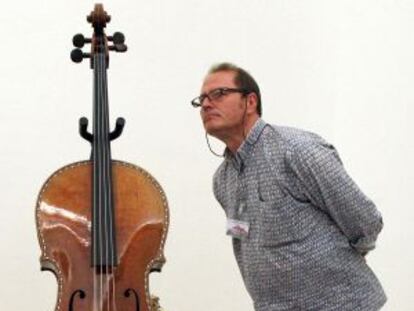 Un visitante observa el violonchelo restaurado en una sala del Palacio Real.