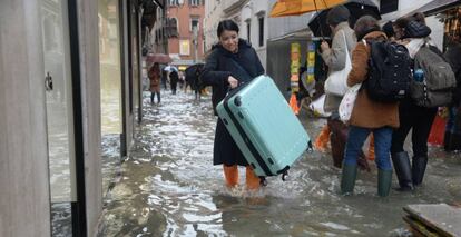 Turistas caminan por las calles inundadas de Venecia este viernes.