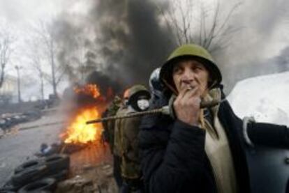 Un manifestante fuma un cigarrillo en las barricadas mientras contin&uacute;an los enfrentamientos con los antidisturbios en la Plaza de la Independencia en Kiev (Ucrania).