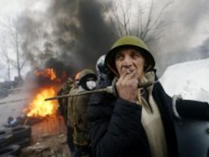 Un manifestante fuma un cigarrillo en las barricadas mientras contin&uacute;an los enfrentamientos con los antidisturbios en la Plaza de la Independencia en Kiev (Ucrania).