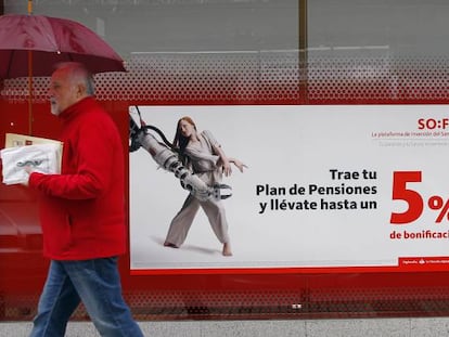 Una persona pasa delante de la una sucursal de Banco Santander donde se promocionan planes de pensiones.