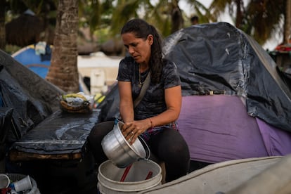 Rose Mary Marcano lava una olla afuera de su carpa para preparar los cafés que vende en la playa a otros migrantes.