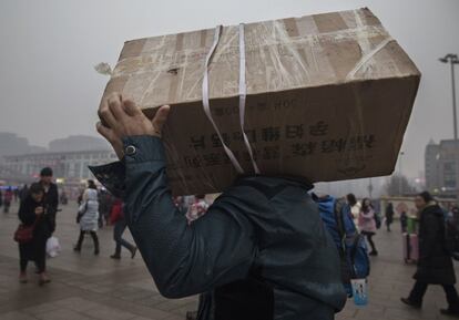 Un viajero transporta una caja en dirección a la estación de tren de Pekín.