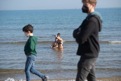 Bañistas y paseantes en el primer día del año 2022, en la playa de la Malvarrosa, en Valencia.