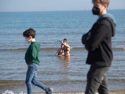 Bañistas y paseantes en el primer día del año 2022, en la playa de la Malvarrosa, en Valencia.