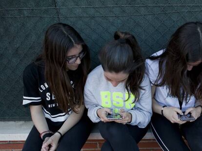 Un grupo de amigas adolescentes usando sus teléfonos móviles.