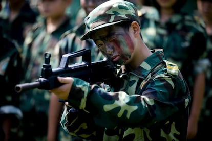 Un niño con uniforme y pintura de camuflaje apunta con su arma durante un entrenamiento en un campamento militar de verano. Durante los dos meses que dura, sus alumnos, con edades de entre seis y 17 años, reciben entrenamiento dirigido por militares, policías y bomberos retirados.