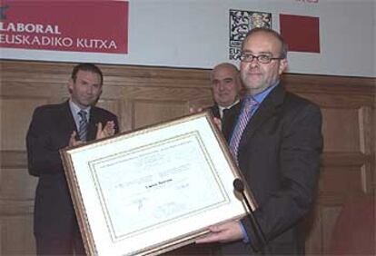 Gurutz Jáuregui tras recibir el diploma que acredita el premio concedido, ante el <i>lehendakari</i> Ibarretxe y Javier Retegi.