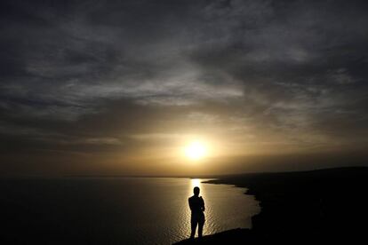 Un turista mira la puesta de sol en el Cabo Greco cerca de Ayia Napa, Chipre.