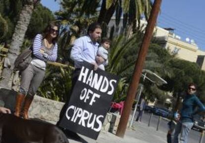 Un hombre sostiene hoy una pancarta en la que se puede leer "mantened vuestras manos lejos de Chipre" frente al Parlamento en Nicosia, como protesta ante el rescate a Chipre.