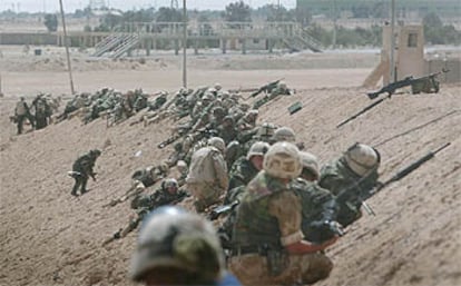 Un grupo de <i>marine</i>s estadounidenses se pone a cubierto tras un talud de tierra para protegerse de los disparos iraquíes en la localidad de Um Qasr, al sur del país.