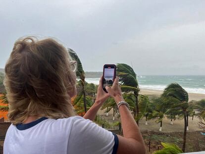 Una turista graba un video de las palmeras moviéndose en el viento con su celular, en Puerto Escondido.