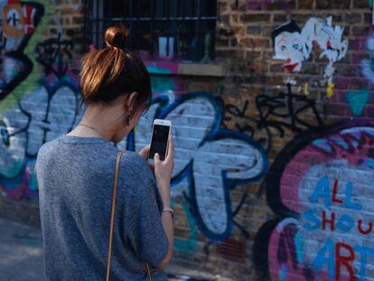 Una joven fotografía un grafiti en Brick Lane, Londres.