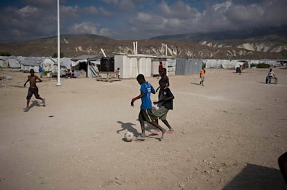 Varios niños juegan a fútbol entre los barracones de un campo de refugiados en Haití.