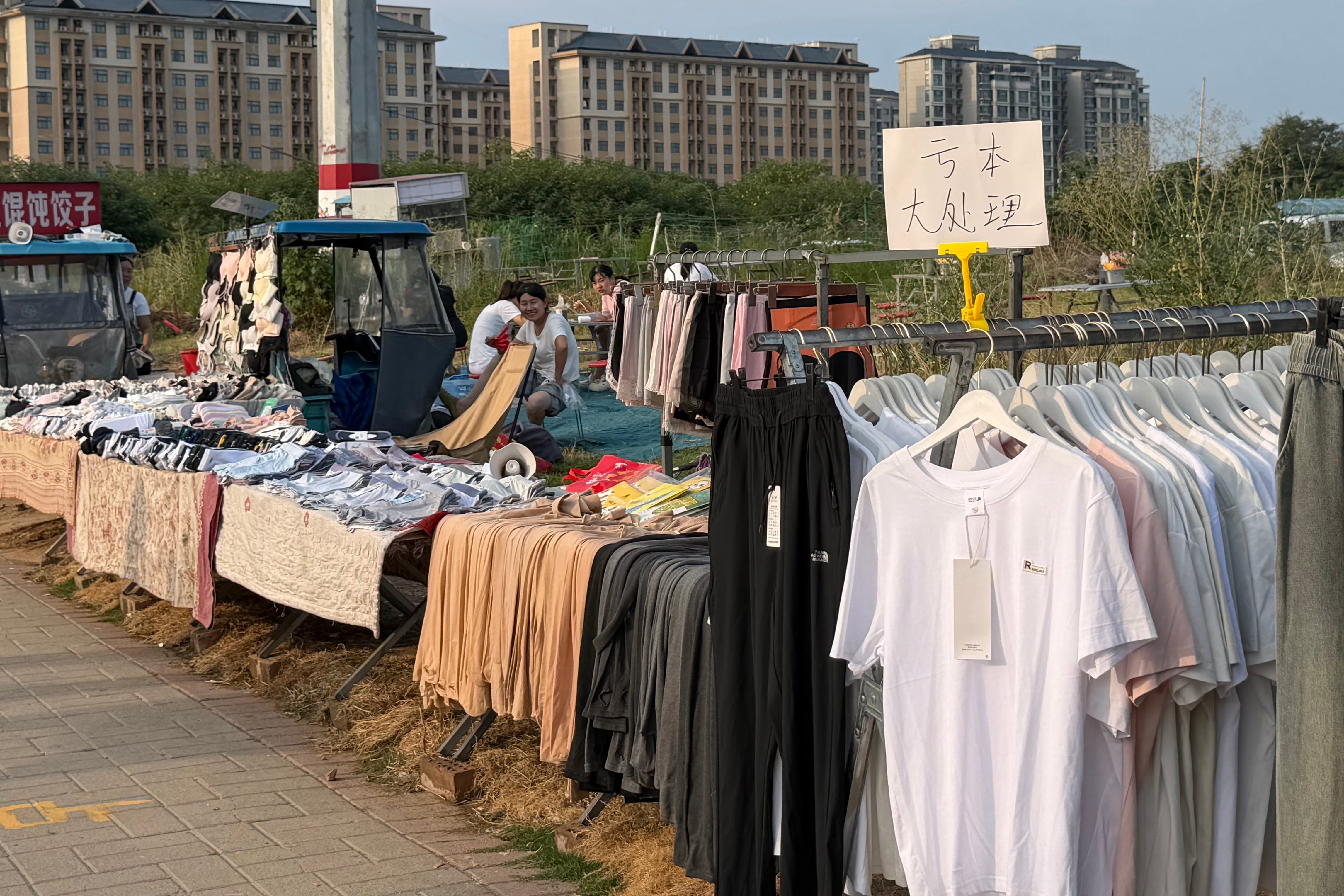 Mujeres venden ropa en un mercadillo ubicado frente a la fábrica de Foxconn de Zhengzhou, China, el 7 de julio de 2026.