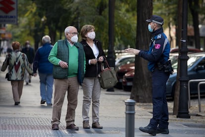 Un agente de la policía local de Madrid informa a una pareja sobre las medidas contra el coronavirus.