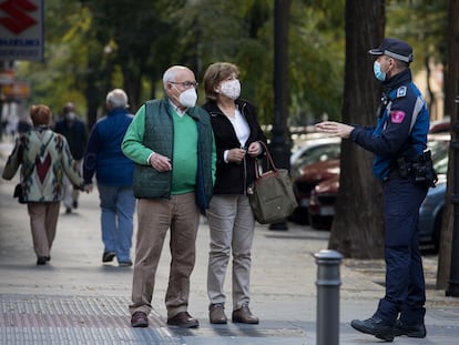 A local police officer informs a couple about the coronavirus restrictions in Madrid.