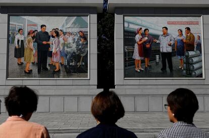 Cidadãos da Coreia do Norte rendem homenagem em frente às pinturas dos líderes norte-coreanos, Kim Il Sung e Kim Jong Il, em uma fábrica de seda em Pyongyang.