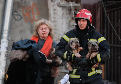 Una bombero ayuda a evacuar a una mujer y sus perros tras el bombardeo ruso contra el centro de Kiev.