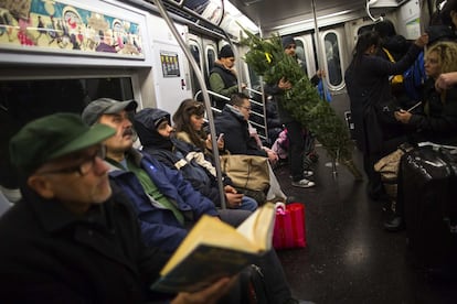 Un hombre sujeta un árbol de navidad en el metro de Nueva York, 29 de noviembre de 2013.