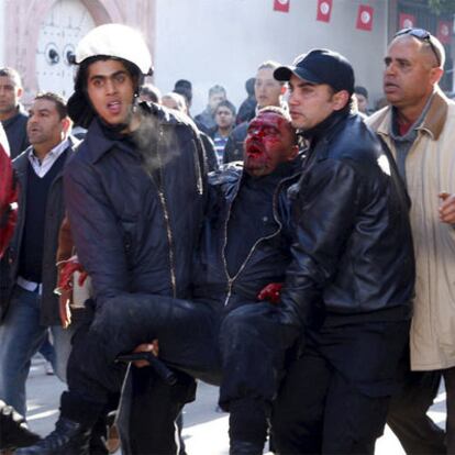Dos policías transportan a un colega herido en una manifestación frente a la sede del Gobierno en Túnez.