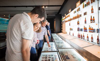 Visitantes del museo de Estrella Galicia contemplan etiquetas y botellas antiguas de la marca.