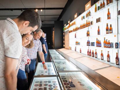 Visitantes del museo de Estrella Galicia contemplan etiquetas y botellas antiguas de la marca.