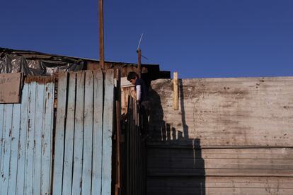 Un niño trepa una barda en un asentamiento a las afueras de Santiago, en mayo de 2020.
