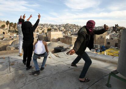 Unos palestinos lanzan piedras hacia unos colonos israelíes asentados en dos viviendas de un edificio de Hebrón por la disputa de la propiedad.