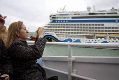 La ministra de Fomento, Ana Pastor, fotografía con su teléfono el crucero AIDA durante la visita que ha realizado hoy a las obras del puente sobre la Bahía de esta ciudad, donde ha subido a la pilastra número 13 de la citada infraestructura, que constituirá un nuevo acceso de 5 kilómetros de longitud a la ciudad.