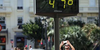 Un hombre toma una fotografía a un termómetro en Valencia, en agosto.