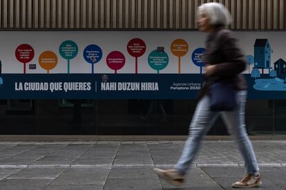 Una mujer camina por delante de un cartel de Agenda Urbana Pamplona 2030, que busca avanzar en el desarrollo de un modelo de ciudad más sostenible, innovador e inclusivo.