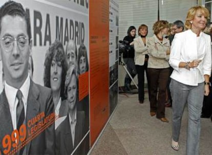 Esperanza Aguirre camina junto a uno de los paneles de la exposición de la Asamblea, en el que aparece su rival Ruiz-Gallardón.