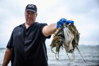 Gary Stokes, fundador de Oceans Asia, posa con mascarillas usadas y tiradas en una playa en las islas Lantau, en Hong Kong (China). El nuevo coronavirus ha provocado más de 390.000 muertes en el mundo y más de 6,6 millones de casos declarados.