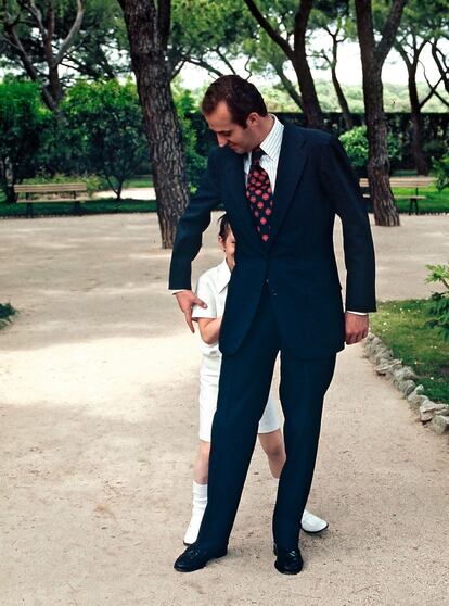 Madrid, 30 de mayo de 1975. El entonces infante Don Felipe se esconde tras su padre, Don Juan Carlos, después de la celebración de la ceremonia de su Primera Comunión en la Capilla del Palacio de la Zarzuela.