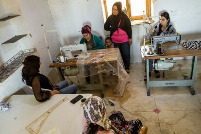 Cihan, una de las aldeanas de Jinwar, enseña a otras aldeanas a usar la máquina de coser, como parte de un proyecto de costura organizado en el pueblo.